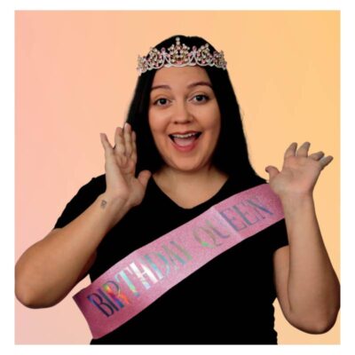 Woman wearing the Birthday Queen Deluxe Crown & Sash Set with a jeweled tiara-style crown and pink glitter birthday sash.