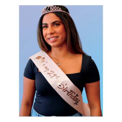Adult wearing the It’s My 21st Birthday Deluxe Crown & Sash Set with a sparkling rose gold-tone 21 tiara and blush-pink birthday sash.