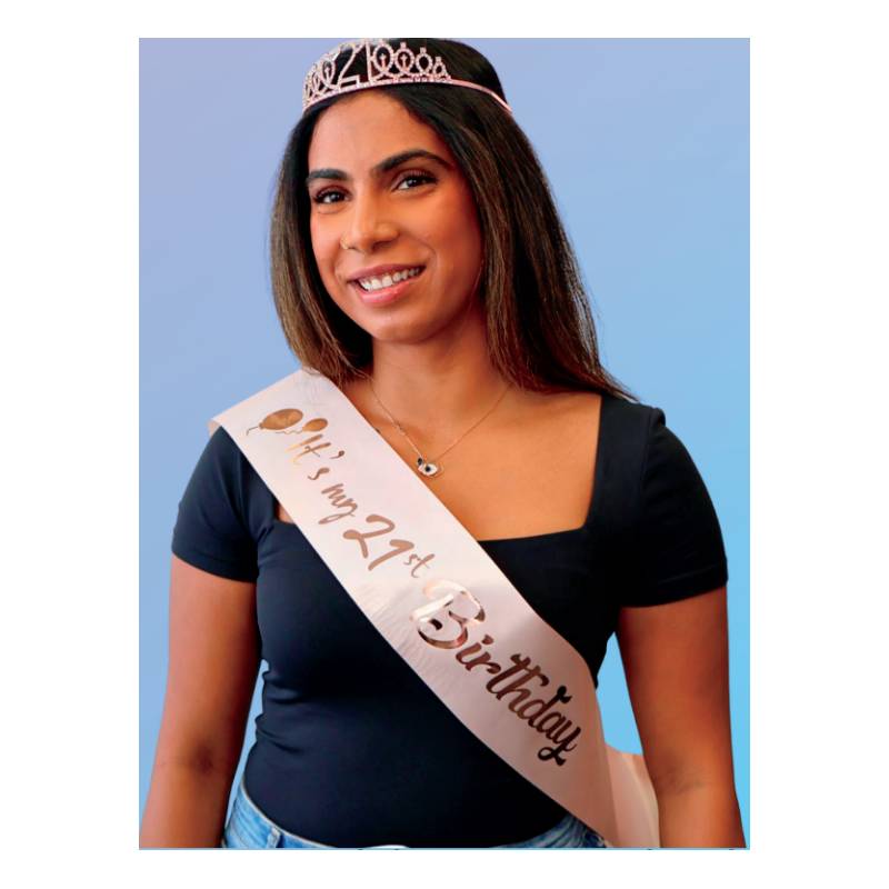 Adult wearing the It’s My 21st Birthday Deluxe Crown & Sash Set with a sparkling rose gold-tone 21 tiara and blush-pink birthday sash.